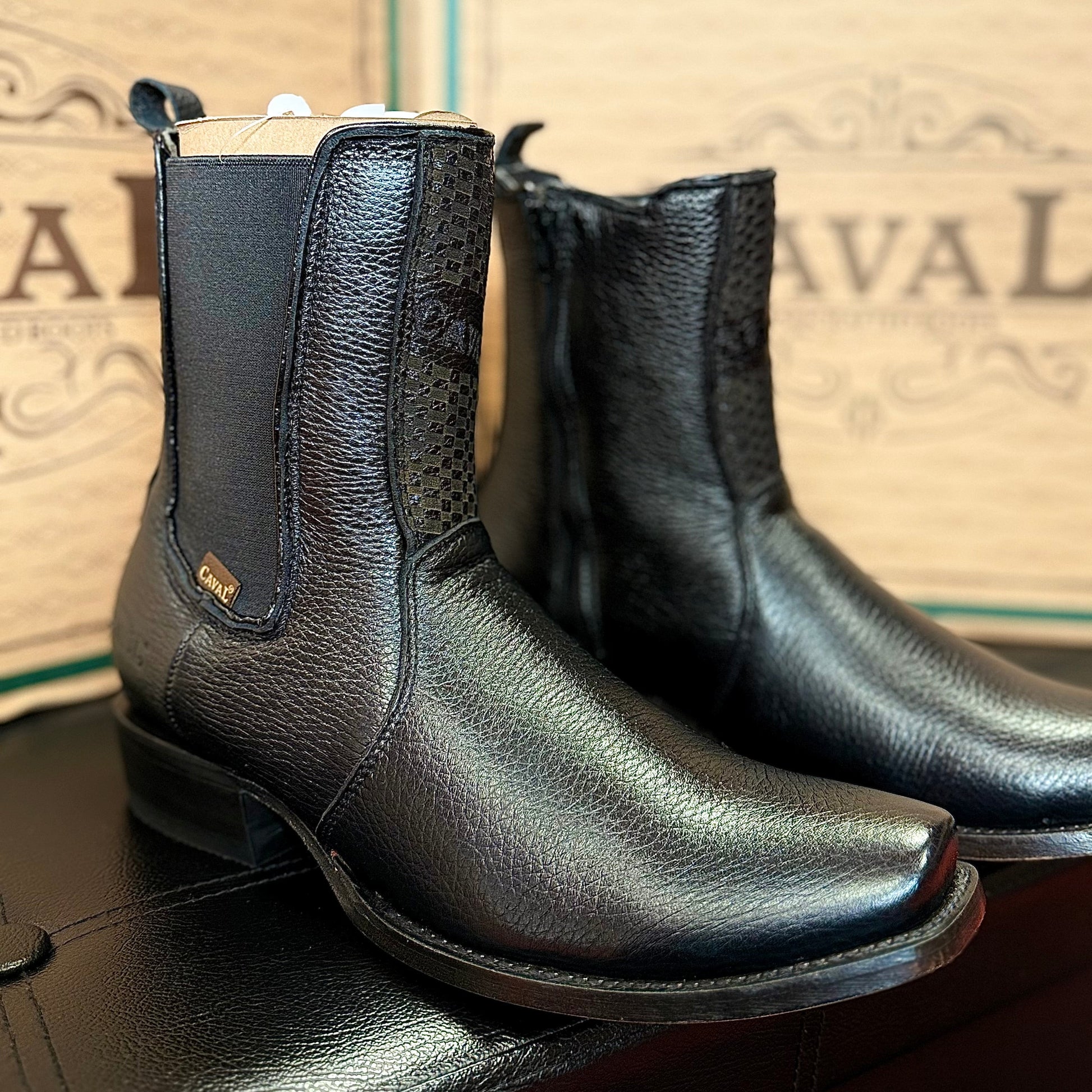 Black leather boots on a surface with a branded box in the background