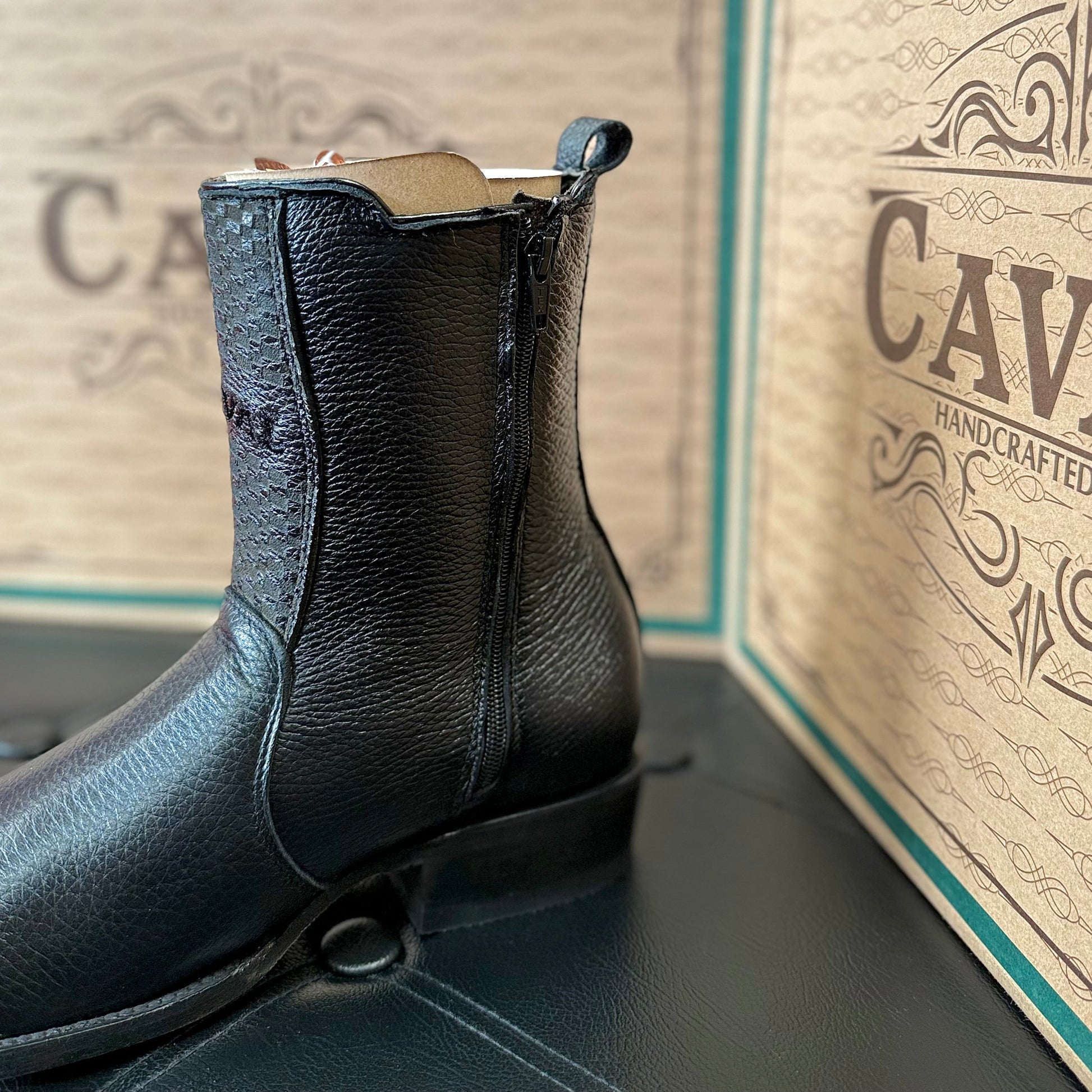 Black leather boot with 'Caval' branding on a matching box.