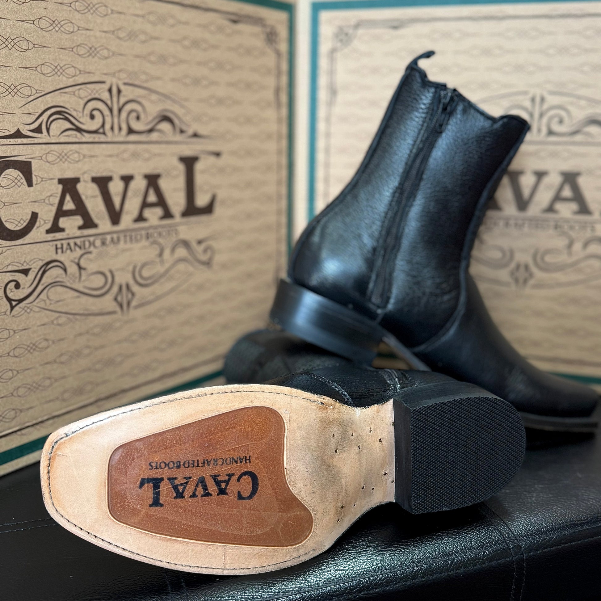 Black leather boot with visible brand name on a branded box